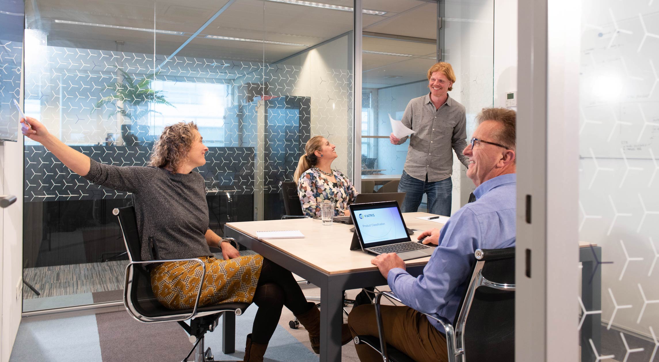 Vergaderruimte van glas met vier Viatris-medewerkers tijdens een brainstormsessie