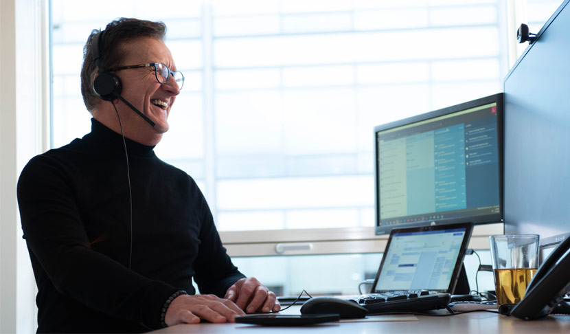 Viatris-medewerker met headset op die achter zijn sta bureau aan het werk is