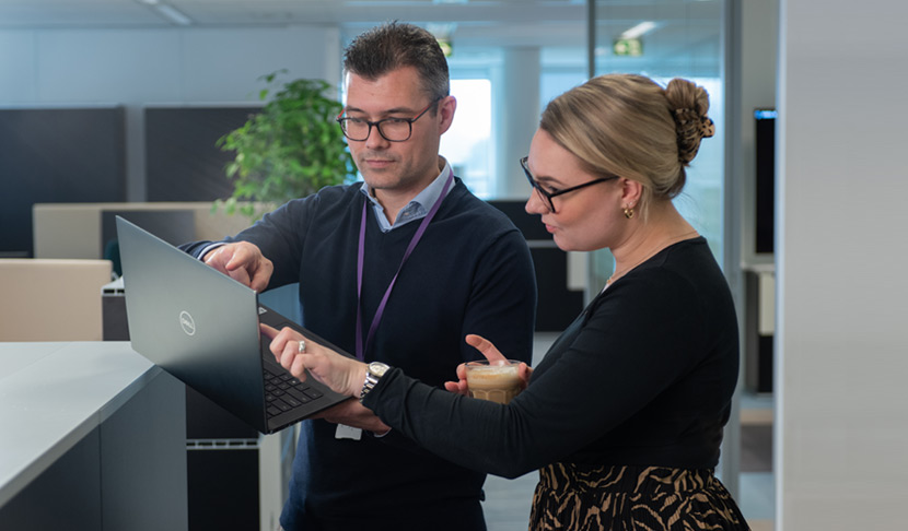 Twee Viatris-medewerkers in kantorentuin met één laptop die elkaar iets uitleggen