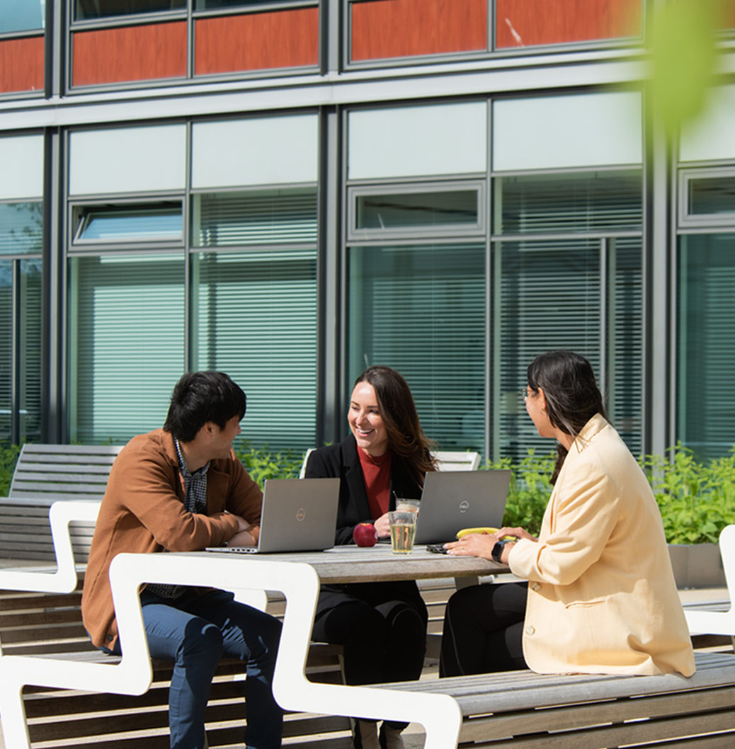 Drie Viatris-medewerkers buiten op een bankje met een laptop die met elkaar in gesprek zijn.