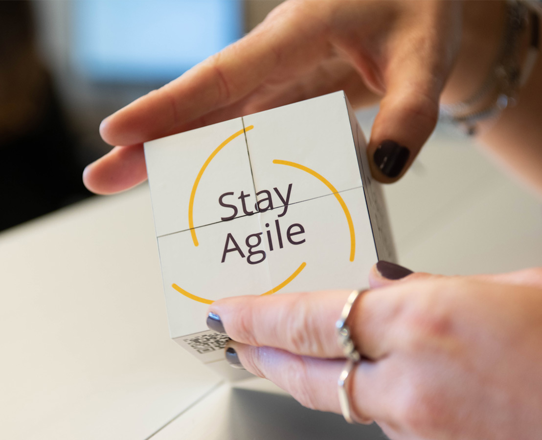Twee handen die kubus vasthouden waarop “Stay Agile” staat afgebeeld