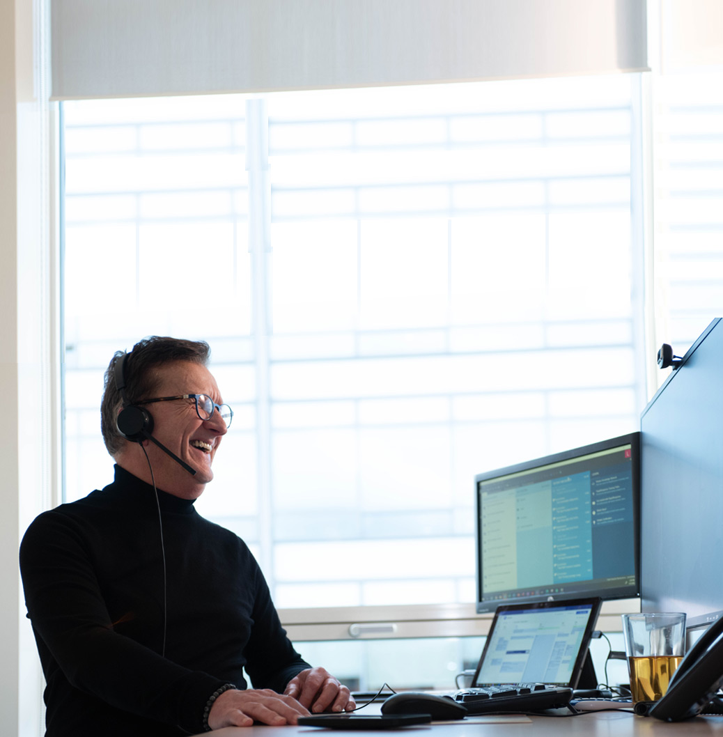 Viatris-medewerker met headset op die achter zijn sta bureau aan het werk is